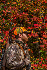 Young man in colorful fall colors hunting with rifle in Oregon