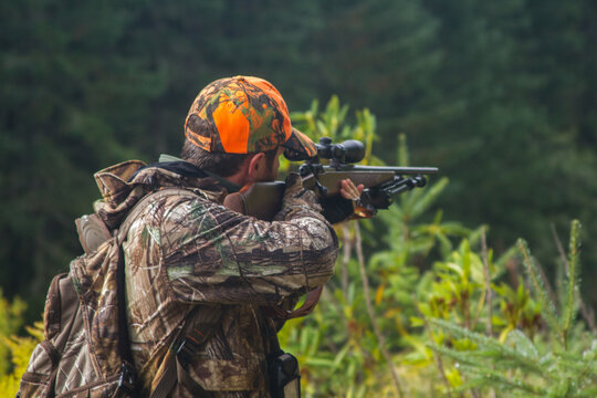 Young hunter aiming rifle in the forest