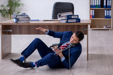 Chained male employee unhappy with excessive work in the office