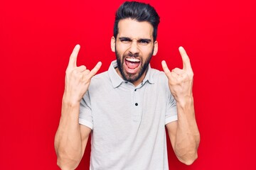 Young handsome man with beard wearing casual polo shouting with crazy expression doing rock symbol...