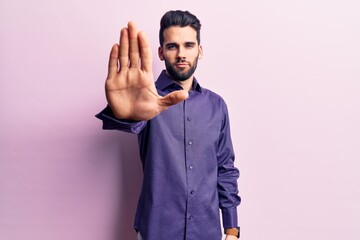 Young handsome man with beard wearing casual shirt doing stop sing with palm of the hand. warning expression with negative and serious gesture on the face.