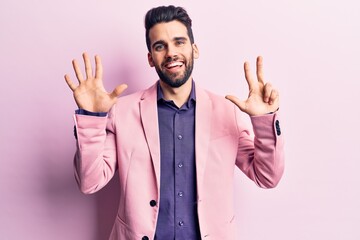 Young handsome man with beard wearing elegant jacket showing and pointing up with fingers number eight while smiling confident and happy.