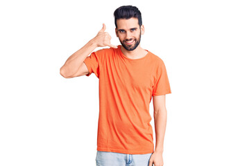 Fototapeta premium Young handsome man with beard wearing casual t-shirt smiling doing phone gesture with hand and fingers like talking on the telephone. communicating concepts.