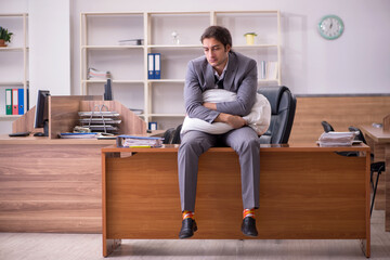 Young male employee sleeping at workplace