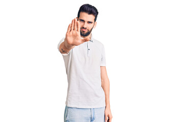 Young handsome man with beard wearing casual polo doing stop sing with palm of the hand. warning...