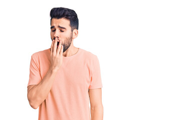 Young handsome man with beard wearing casual t-shirt bored yawning tired covering mouth with hand. restless and sleepiness.