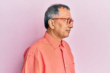 Middle age indian man wearing casual clothes and glasses looking to side, relax profile pose with natural face with confident smile.