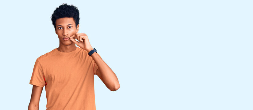 Young african american man wearing casual clothes mouth and lips shut as zip with fingers. secret and silent, taboo talking