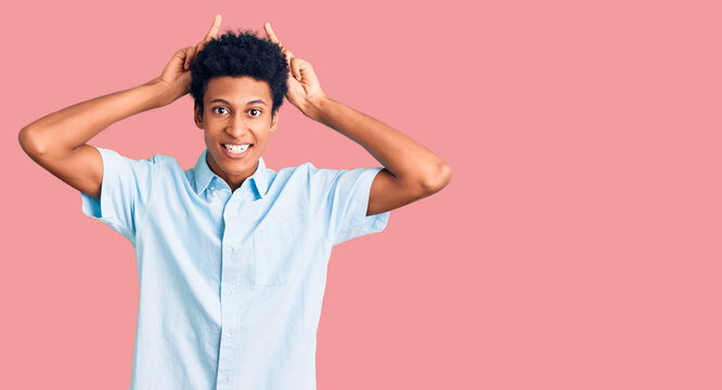 Young african american man wearing casual clothes posing funny and crazy with fingers on head as bunny ears, smiling cheerful