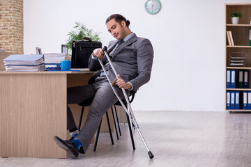 Young leg injured male employee working in the office