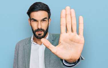 Young hispanic man wearing business clothes doing stop sing with palm of the hand. warning...