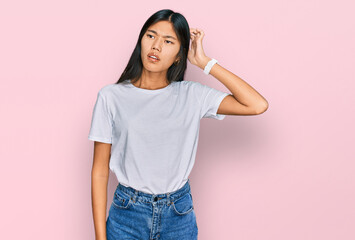 Beautiful young asian woman wearing casual white t shirt confuse and wondering about question....
