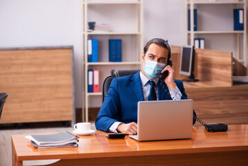 Fototapeta premium Young male employee working in the office wearing mask