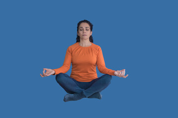 Brunette woman levitating and doing yoga, on a blue background