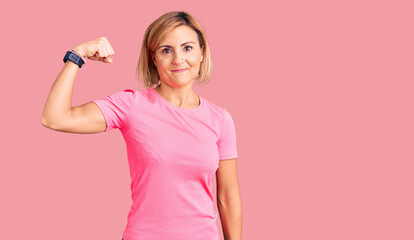 Young blonde woman wearing sportswear strong person showing arm muscle, confident and proud of power