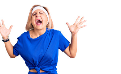 Young blonde woman wearing sportswear celebrating mad and crazy for success with arms raised and...