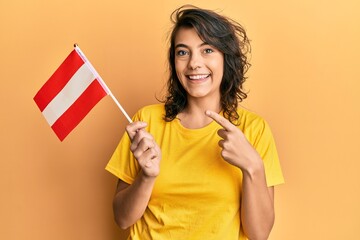Young hispanic woman holding austria flag smiling happy pointing with hand and finger
