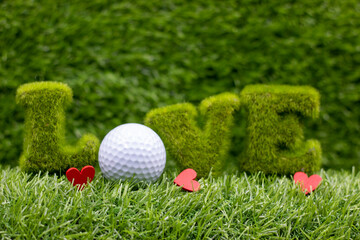 Naklejka premium Golf ball with red heart on green grass background