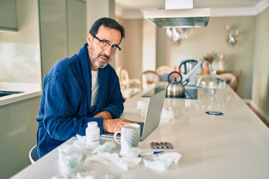 Middle age man feeling sick with cold and fever at home, ill with flu disease working from home
