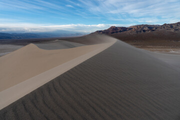 Strong wind blowing sand off the ridge of a sand dune, creating ripples, Eureka Dunes, Death Valley National Park, California