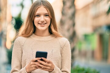 Beautiful caucasian teenager smiling happy using smartphone at the city.