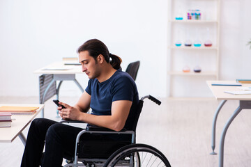 Young male student in wheel-chair preparing for exams