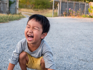 Asian cute little child boy laughing with mouth open wide, seeing whitening teeth. Happy Kid in white shirt enjoy in funny shot in relaxing day.