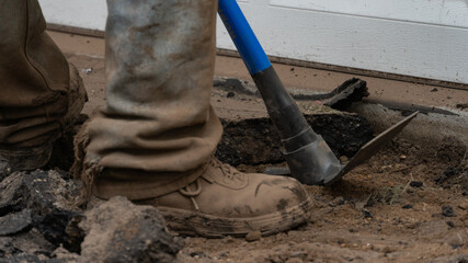 breaking up an asphalt driveway with a sledgehammer and a pickax 