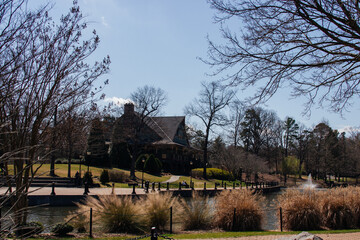 A park in early spring on sunny day,which depicts reservoir,visible through the branches of trees without leaves,house behind it,and the grass in the foreground.Cleveland Park in Spartanburg, SC, USA 