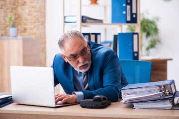 Old male bookkeeper unhappy with excessive work at workplace