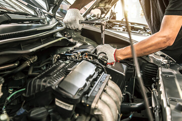 Close-up hands of auto mechanic are using the wrench to repair and maintenance auto engine is problems at car repair shop. Concepts of car care check and fixed and services insurance.