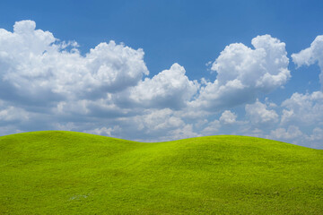 Green grass field on blue sky with cloud background. Green meadow under blue sky with clouds.