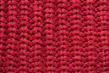 Red knitted fabric as an abstract texture. Knitting, elastic band pattern, English elastic band. Close-up. 
