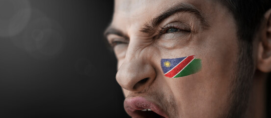 A screaming man with the image of the Namibia national flag on his face