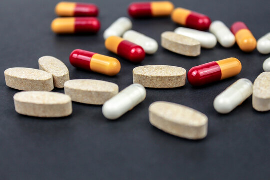 Heap of colorful medication and pills, capsules on black background. Top view, flat lay. Close-up.