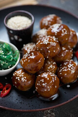 Roasted pork meatballs in teriyaki sauce with sesame seeds and seaweed salad, vertical shot, close-up