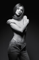 Fototapeta na wymiar Studio portrait of sexy young woman. Seductive lovely girl dressed in jeans. Sensual lady, topless. Black and white