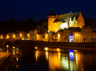Fototapeta premium View from Mayenne river of illuminated castle and bridge of Laval town at summer night, southwestern France
