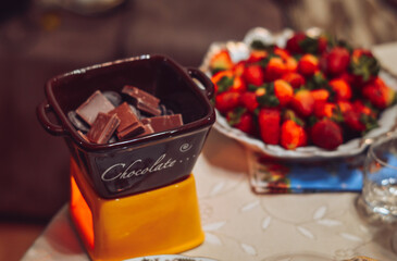 Chocolate fondue with fresh strawberries on the background of a Christmas tree.