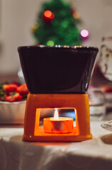 Chocolate fondue with fresh strawberries on the background of a Christmas tree.