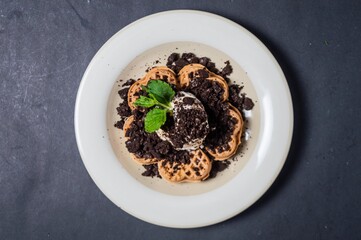 Chocolate waffles with chocolate biscuit slices sprinkled and given vanilla ice cream