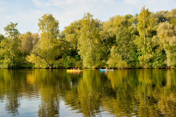 Fototapeta na wymiar Kayaking on the river. Autumn trees. Park zone in Strogino, Moscow - September 24, 2020
