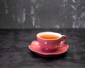 Green tea in a pink mug with white peas on a gray background