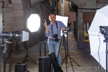 Portrait of positive photographer with his camera during professional photo shooting on town street