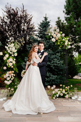 Fototapeta premium outdoor wedding ceremony in an arch of living flowers.Beautiful couple newlyweds