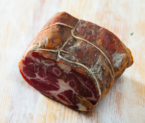 Piece of appetizing cured pork tenderloin on wooden surface. Popular meat delicacy