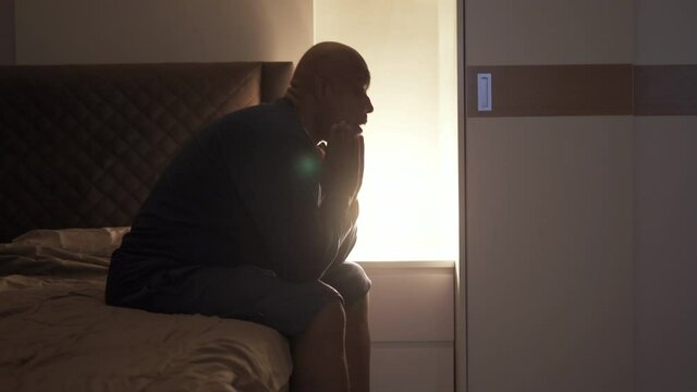 Depressed lonely old elderly black man. African American people sitting on bed in bedroom at home. Lifestyle on late night. Insomnia. Quarantine