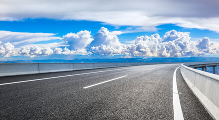 Fototapeta premium Empty asphalt road and blue sky with white clouds.Road background.