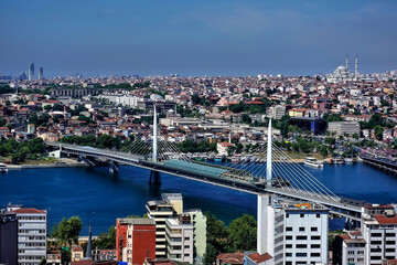 Fototapeta na wymiar Panorama of Istanbul from above. In the foreground is the bridge over the Bosphorus. There are many old and modern city buildings in the distance. Summer sunny day. Turkey