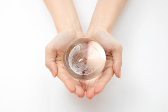 Closeup Shot Of Hands Holding A Glass Globe On A White Background